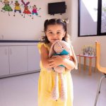 Girl in a yellow dress with a toy in the room