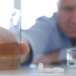 A man reaches for a glass of alcohol