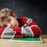 A tired boy lies on his desk